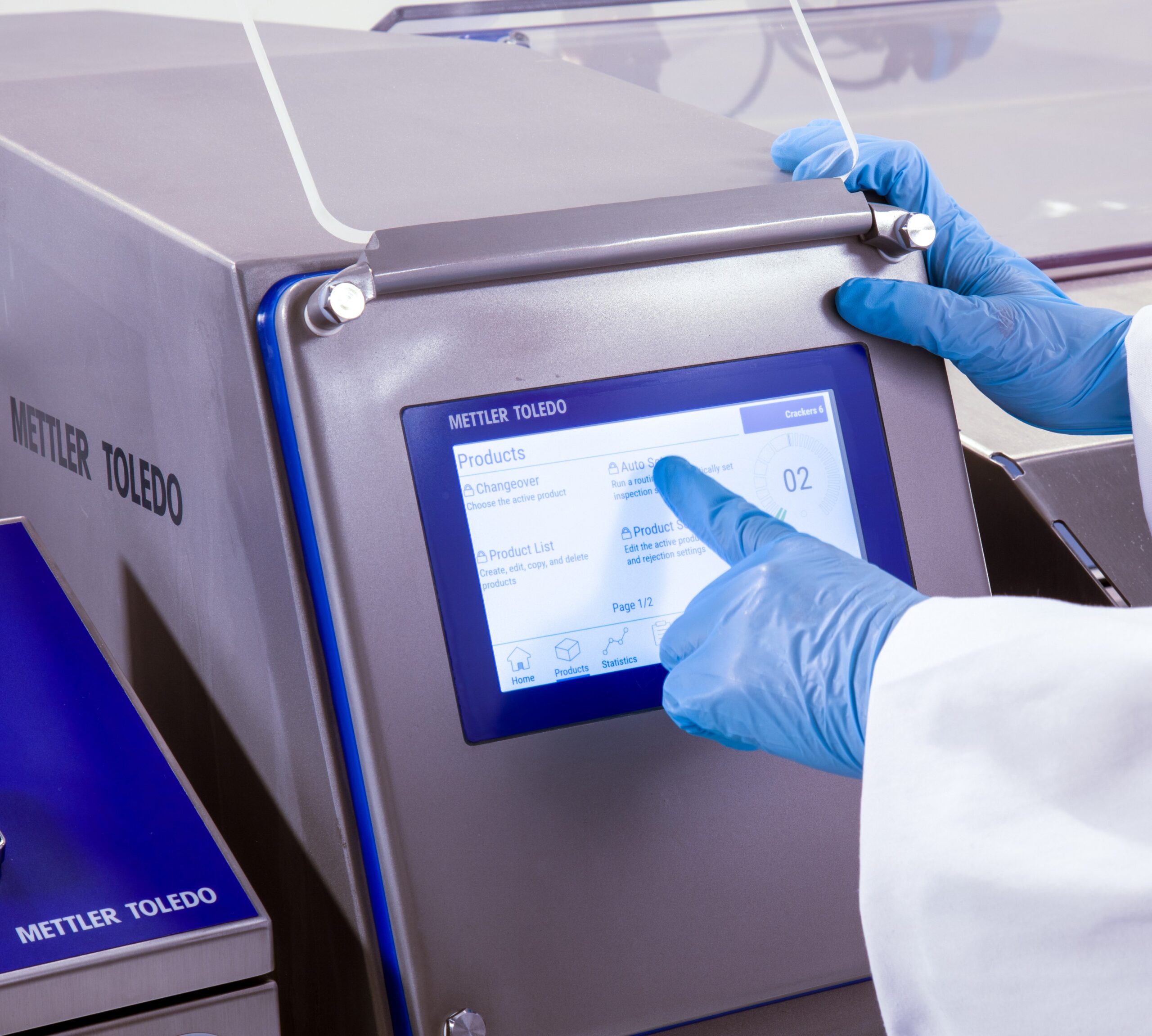 Ekran Mettler Toledo metal detektora i ruka operatera koja pririska opcijua na touch screen ekranu.