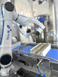 Kobot ruka na proizvodnoj liniji pakuje limenke proizvoda iz mesne industrije u kutiju i automatizuje proces pakovanja.