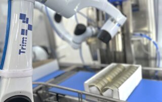 Kobot ruka na proizvodnoj liniji pakuje limenke proizvoda iz mesne industrije u kutiju i automatizuje proces pakovanja.
